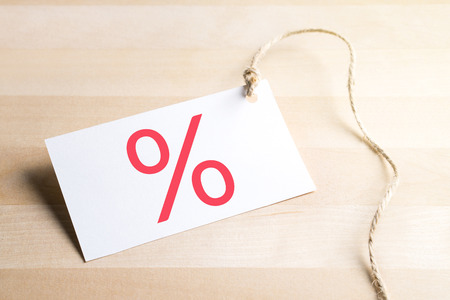 Bargain prices, sale and special offer concept. Price tag with percent symbol on wooden table.の写真素材