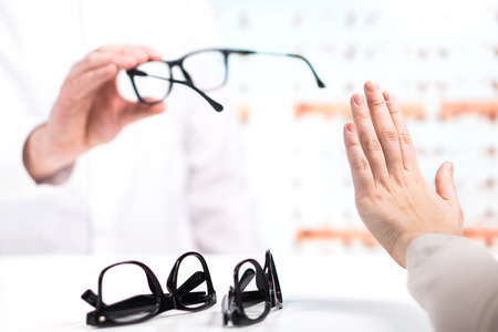 Problem at optician. Unhappy customer refuse to try or don't like new glasses. Bad service in spectacles store. Disappointed and angry patient. Too expensive eyeglasses.の写真素材