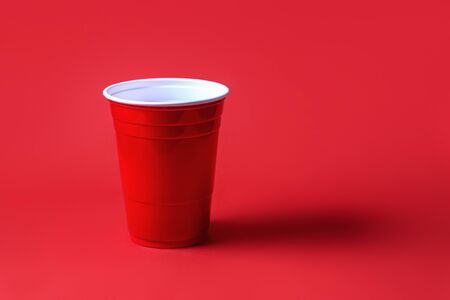 Red party cup on red background. Beer pong tournament or college celebration concept.の写真素材