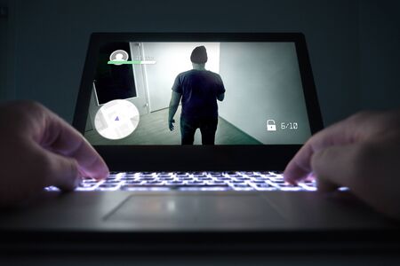 Teenage boy or young man playing action or crime video game with laptop. Computer and online gaming...