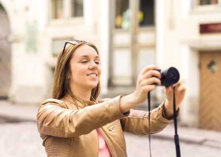 Smiling woman taking photos with digital camera in old city street. Holiday pictures on vacation....