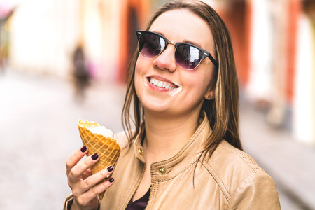 Ice cream on messy face. Happy laughing woman eating melting and dripping ice cream in the city.