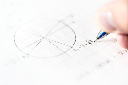Student doing math homework or mathematics test in school class. Writing mathematical equation and numbers for geometry assignment on paper with pen. Notes during lesson and teaching. Schoolwork.の写真素材