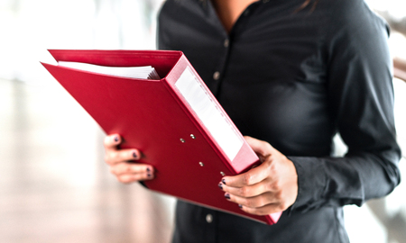 Professional business woman holding folder full of paper documents. Lawyer, legal adviser, office assistant or company manager with binder.の写真素材