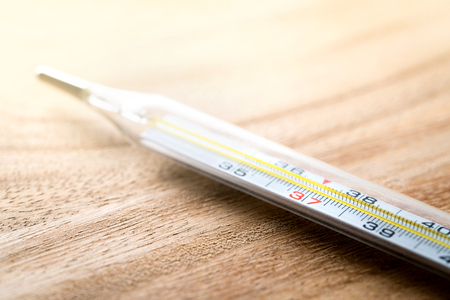 Celsius thermometer on wooden table. Having fever, flu, sickness, virus and being sick concept. Body temperature measurement in health care and medical business.の写真素材