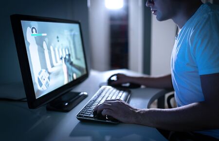 Young man playing video game late at night at home. Gamer streaming fps videogame online. First...