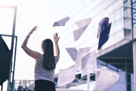 Business woman throwing work papers in the air. Stress from workload. Person going home or leaving...