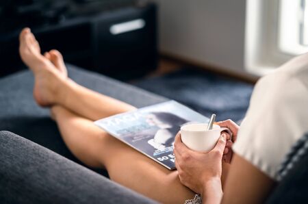 Sunday morning with magazine and coffee. Happy millennial woman relaxing with fashion and beauty...