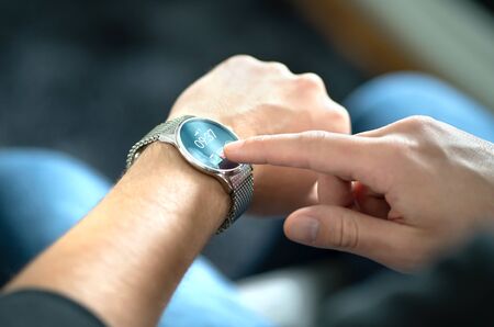 Man touching smart watch screen to open notification and read message. Wearable hybrid mobile device, gadget and activity tracker in wrist. Wearing digital smartwatch in hand. People with wearables.の写真素材