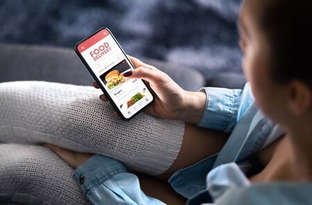 Food delivery app in mobile phone. Restaurant order online. Woman using smartphone to get take away...