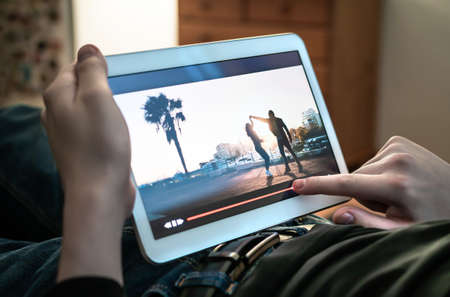 Man watching movie stream. Person using the player timeline to rewind or skip parts of an online video. Bad entertainment or slow internet. Tv series in an on demand streaming site. Digital VOD tech.の写真素材