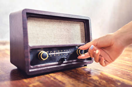 Retro radio tuning. Woman using old vintage music equipment. Adjusting volume or frequency tuner knob. Turning on or off stereo receiver or speaker. Changing channel or station with dial button.の写真素材
