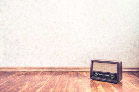 Retro vintage radio background with old wall paper texture pattern. Nostalgia music backdrop and wallpaper. 50s style stereo receiver and speaker on wooden floor. Rustic propaganda news show banner.の写真素材