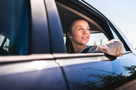 Passenger in taxi or woman in car sitting on the backseat looking outside the window. Happy female...