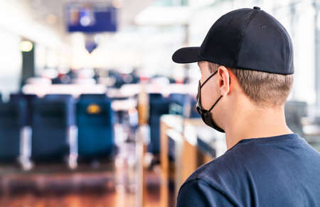 Mask at airport. Man waiting for flight in terminal.. Corona virus, covid19 and travel. Tourist wearing facemask during pandemic at gate. Social distance in public. Vacation after coronavirus vaccine.の写真素材