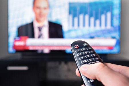 Tv news reporter in television screen and remote control. Man watching presenter, anchor or newsreader in studio. Breaking newstcast channel and live financial statistics network or politics broadcastの写真素材