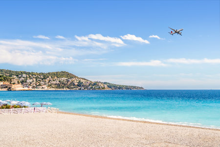 Beach and plane. Flight to vacation destination by the sea. Holiday landscape. Airline flying to summer paradise. Airplane on blue sky and turquoise water in Nice, France. Riviera hotel resort.の写真素材