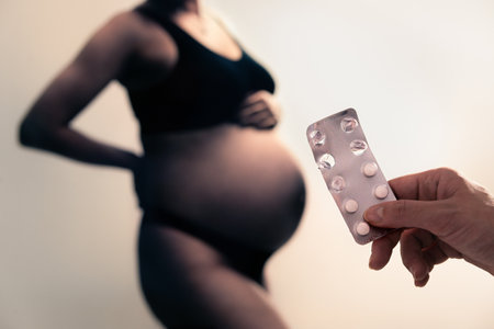 Pregnancy and medicine. Pregnant and pills for vitamins or iodine. Anemia, iron shortage and deficiency. Supplement for woman. Holding tablet in hand. Zinc or calcium.の写真素材