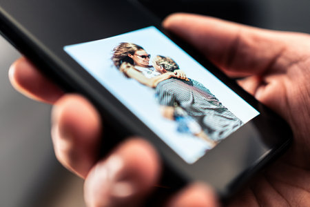 Picture of couple in phone. Sad man looking at photos of woman. Husband longing and missing wife. Memories of happy family. Upset boyfriend or widow.の写真素材