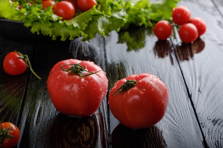 Salad and tomatoes on a black board.の写真素材