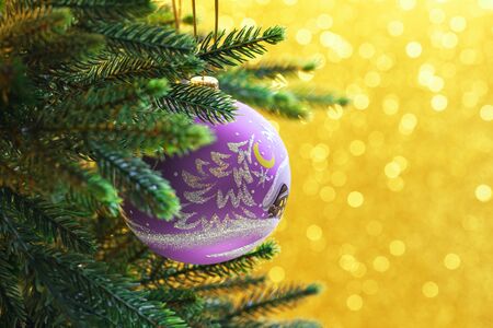 Lilac christmas balls on a gold background with bokehの写真素材