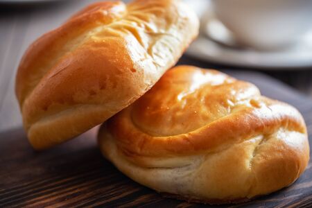 Homemade baking. Fresh and rosy buns with cherry on a wooden table and a cup with fragrant tea.の写真素材