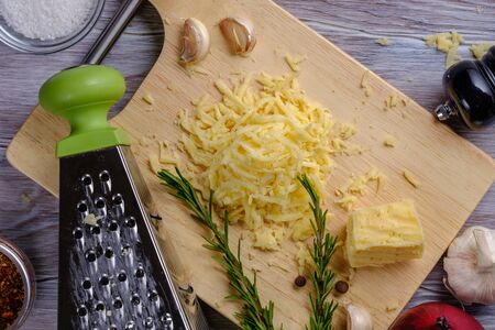 Soft grated cheese on a wooden board with a grater close-upの写真素材