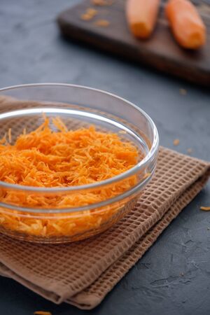 Juicy and fresh grated carrots on a wooden board on a dark background close-upの写真素材
