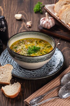 Fragrant chicken soup with egg with garlic and herbs on a wooden table close-upの写真素材