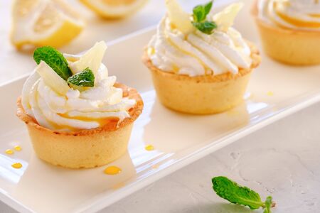 Tartlets with lemon kurd and italian meringue on a white plate close-upの写真素材