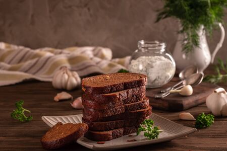 Black bread croutons with garlic and herbs with sauce on a wooden tableの写真素材