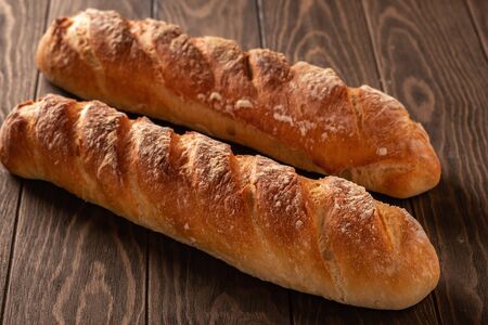 Fresh and tasty french baguette with a crispy crust on a wooden table close-up
