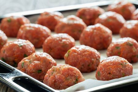 Raw cutlets of ground beef with carrots and herbs before the oven on a baking closeupの写真素材