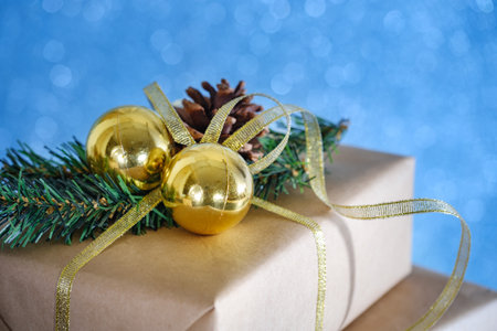 Christmas gift wrapped in paper on an old table with pine cones and a branch of a christmas treeの写真素材