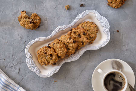 Fragrant oatmeal biscuits on a plate with openwork edges on a gray table close-up