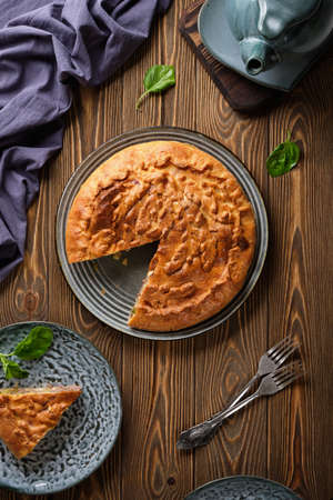 Delicious pie with meat and potatoes with a crispy crust on a blue plate on a wooden table close-upの写真素材