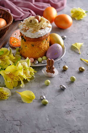 Easter cake with colored eggs and yellow flowers on a gray background close-up