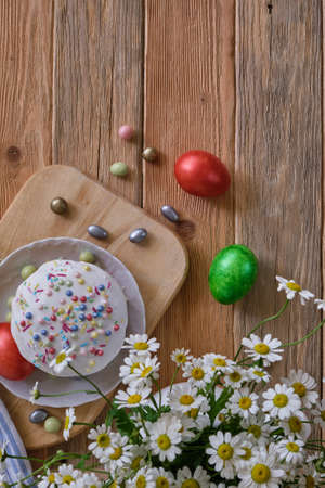 Easter cake with colored eggs and wild chamomiles on the old wooden table close-upの写真素材