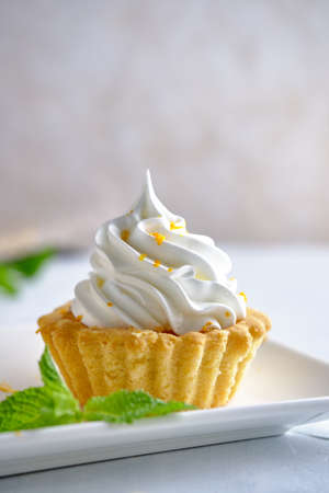 Tartlets with orange jam and protein cream decorated with orange zest on a white plate close-up