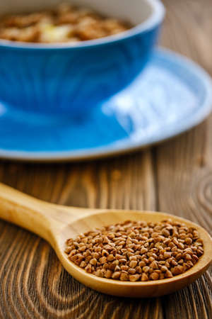Fresh and tasty buckwheat porridge with butter in a blue cup on a wooden tableの写真素材