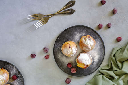 Fragrant lemon muffins with cherry on a black plate on a gray background close-up
