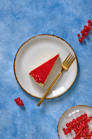 Cheesecake with red currant and black coffee on a blue backgroundの写真素材