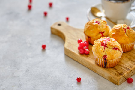 Muffins with red currants on a wooden boardの写真素材