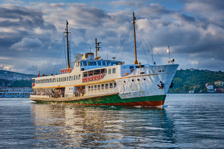 Istanbul, Turkey, A ferry sails along the Bosphorus in the Besiktas area near the Ortakoy pier and the Bosphorus bridgeの写真素材