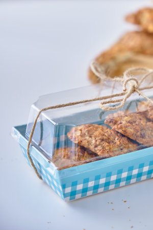 Fresh and crispy oatmeal cookies with nuts and chocolate in a blue box on a white background