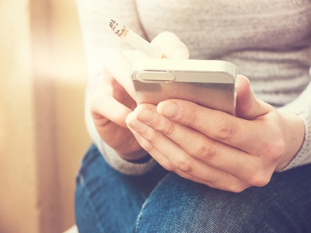 typing at smartphone with beautiful sunlight in the backgroundの写真素材