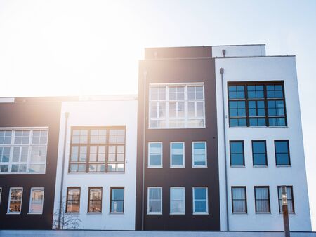 Front view of four connected townhouse apartments with bright sunny glare in the sky
