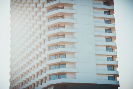 Cropped view of tall white residential building with sunlight glare on bright dayの写真素材