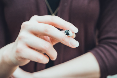 Young woman smoking a cigarette in a conceptual close up view of her hand holding the cigaretteの写真素材