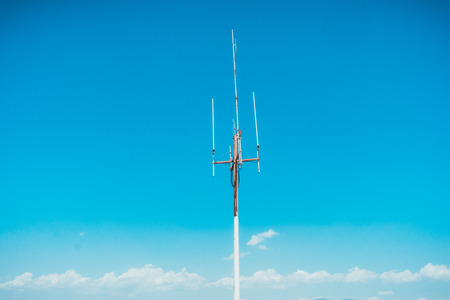 Tall very high frequency antennas on tower mast surrounded by blue sky with copy spaceの写真素材